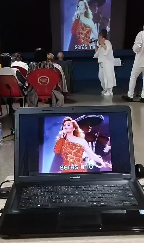 El ordenador con el vídeo karaoke «Serás mío» y, al fondo, Angie y Albert cantando